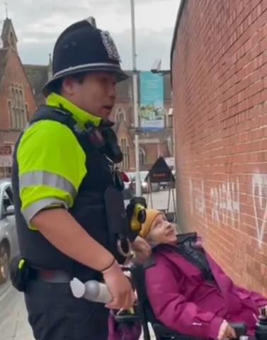 A Portsmouth police officer questions peace activist Rosy Bremer and confiscates her spraycan - in front of her spraypainted Gaza solidarity message.